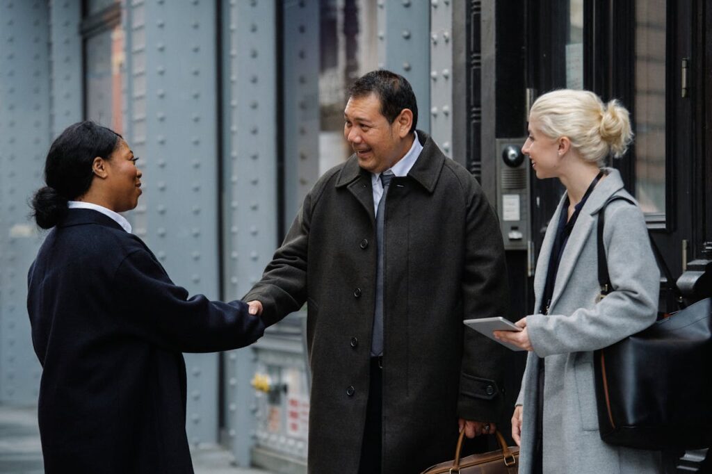 A diverse group of professionals meeting and greeting with a handshake outdoors.